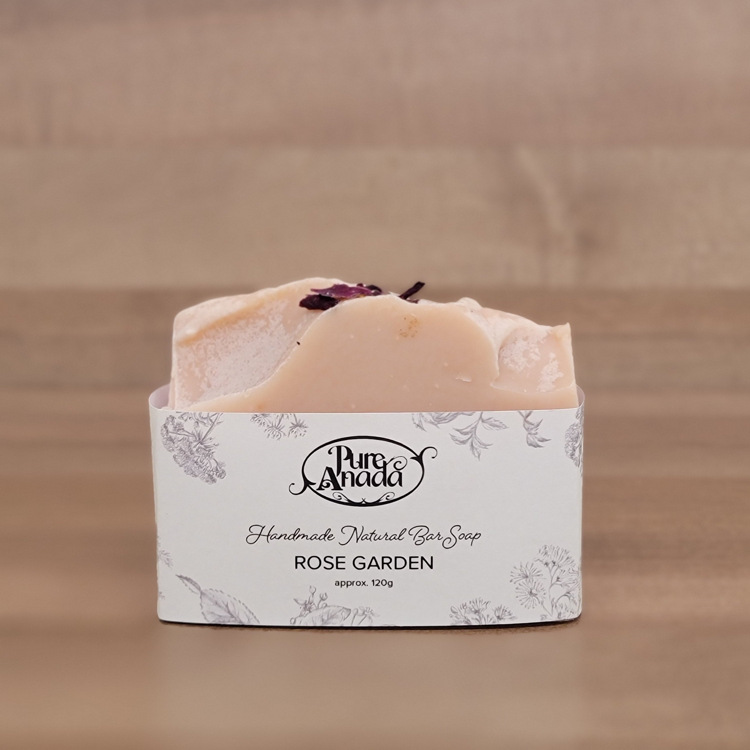 Bar of rose garden handmade natural soap with a decorative label on a wooden surface